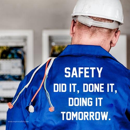 Safety poster showing an electrician wearing a hard hat and holding cables working on an electrical panel with text on the back of his bright blue shirt.
