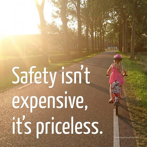 A safety poster showing a little girl riding her bike down a road on a sunny day with the slogan safety isn't expensive, it's priceless.