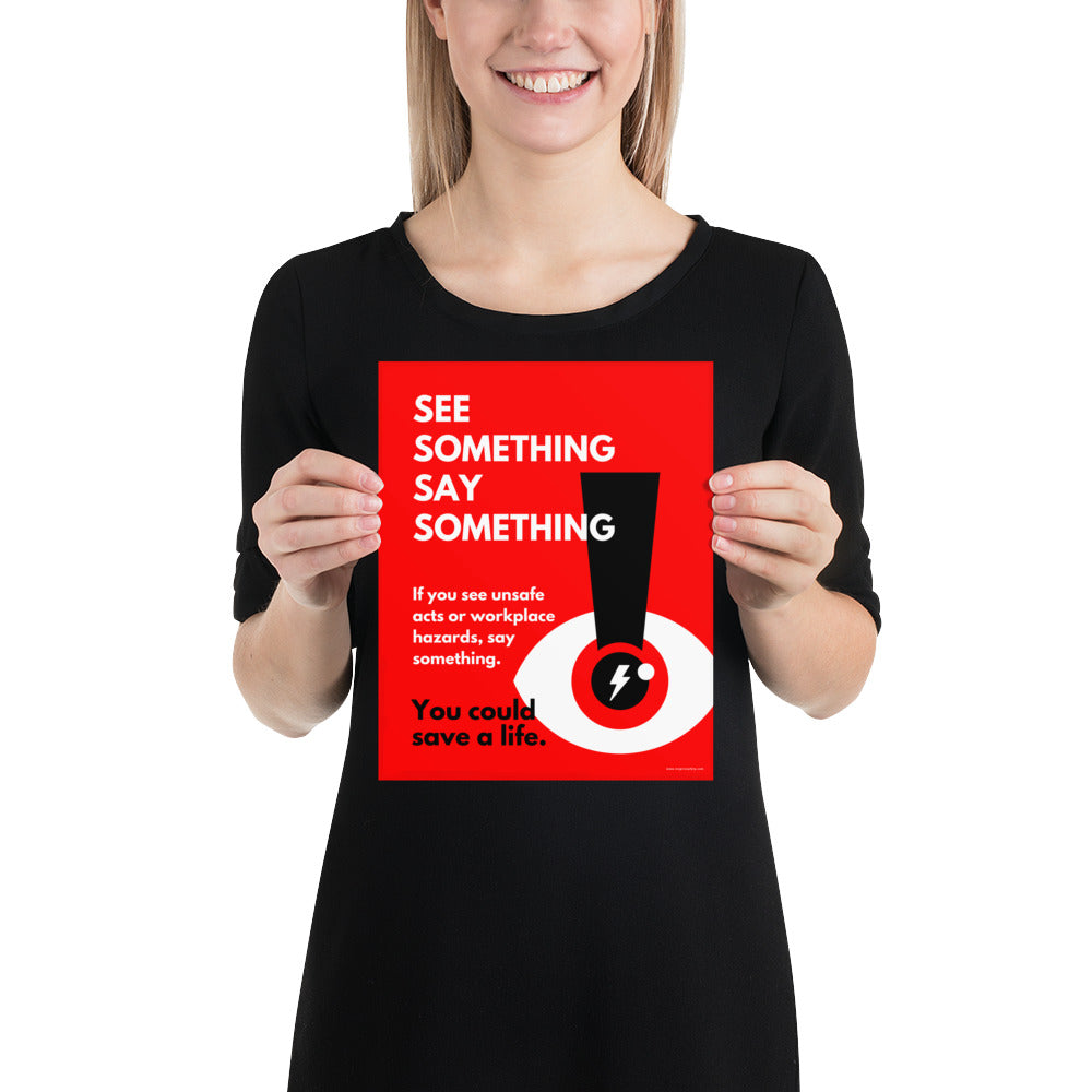 A workplace safety poster with a bright red background an an eye with an exclamation point coming from the pupil and a lightning bolt in the middle of the pupil with text that says "See Something Say Something" in bold lettering with the words "If you see unsafe acts or workplace hazards, say something. You could save a life."