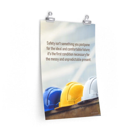 A workplace safety poster showing 3 multi colored hardhats sitting on a wall with the slogan safety isn't something you postpone for the ideal and comfortable future. It's the first condition necessary for the messy and unpredictable present.