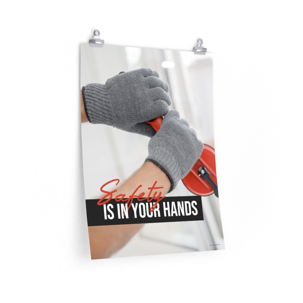 A workplace safety poster showing a close-up of a worker's hands wearing gloves while installing windows with the slogan safety is in your hands.