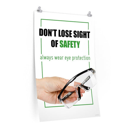 An eye safety slogan showing a close up of a hand presenting out safety glasses with a safety slogan in blue text above.