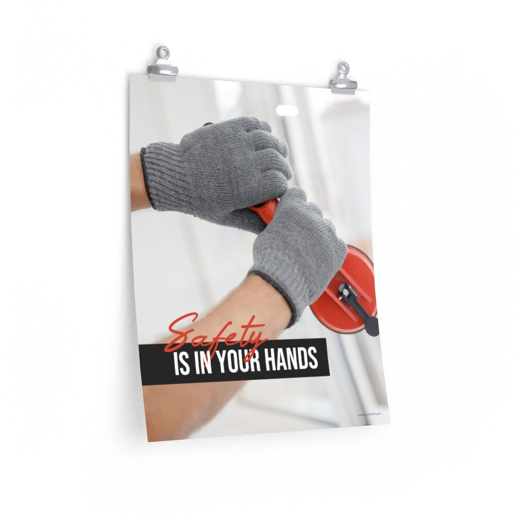 A workplace safety poster showing a close-up of a worker's hands wearing gloves while installing windows with the slogan safety is in your hands.