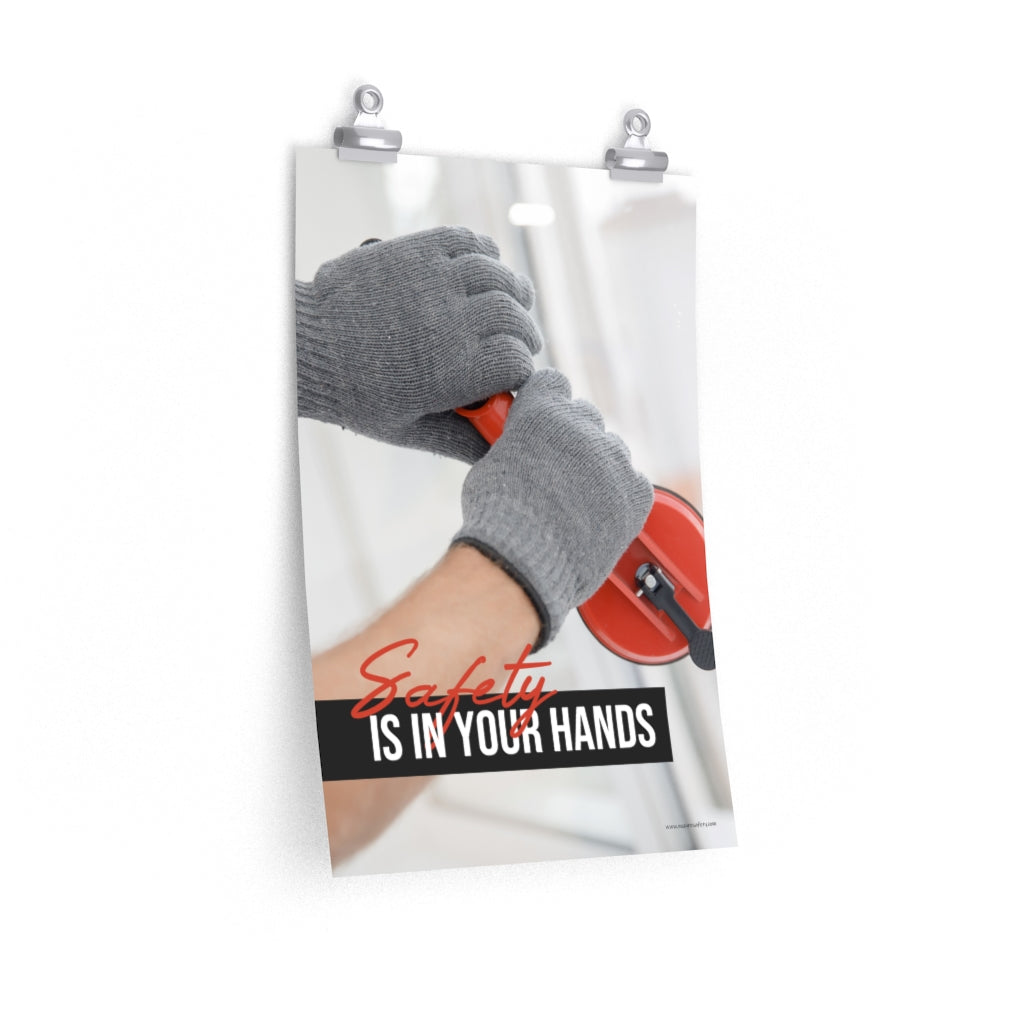 A workplace safety poster showing a close-up of a worker's hands wearing gloves while installing windows with the slogan safety is in your hands.