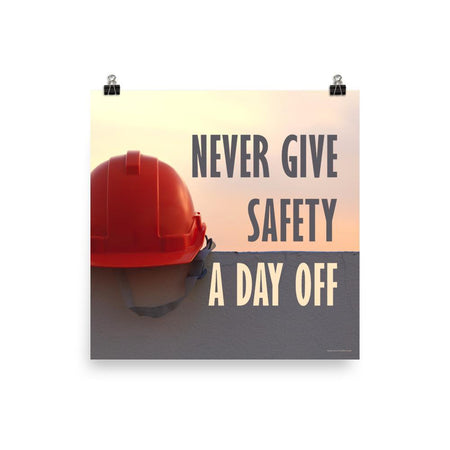 A workplace safety poster depicting a red hard hat sitting on a concrete wall with a dreamy pink sunset in the background with the text never give safety a day off to the right.