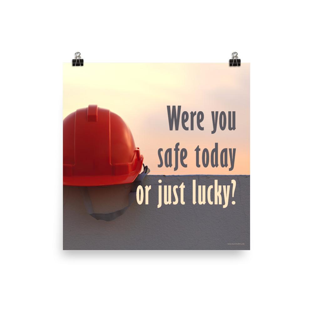 A workplace safety poster showing a red hard hat sitting on a grey wall with a dreamy sunset background and the slogan were you safe today, or just lucky?