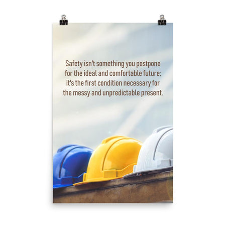 A workplace safety poster showing 3 multi colored hardhats sitting on a wall with the slogan safety isn't something you postpone for the ideal and comfortable future. It's the first condition necessary for the messy and unpredictable present.