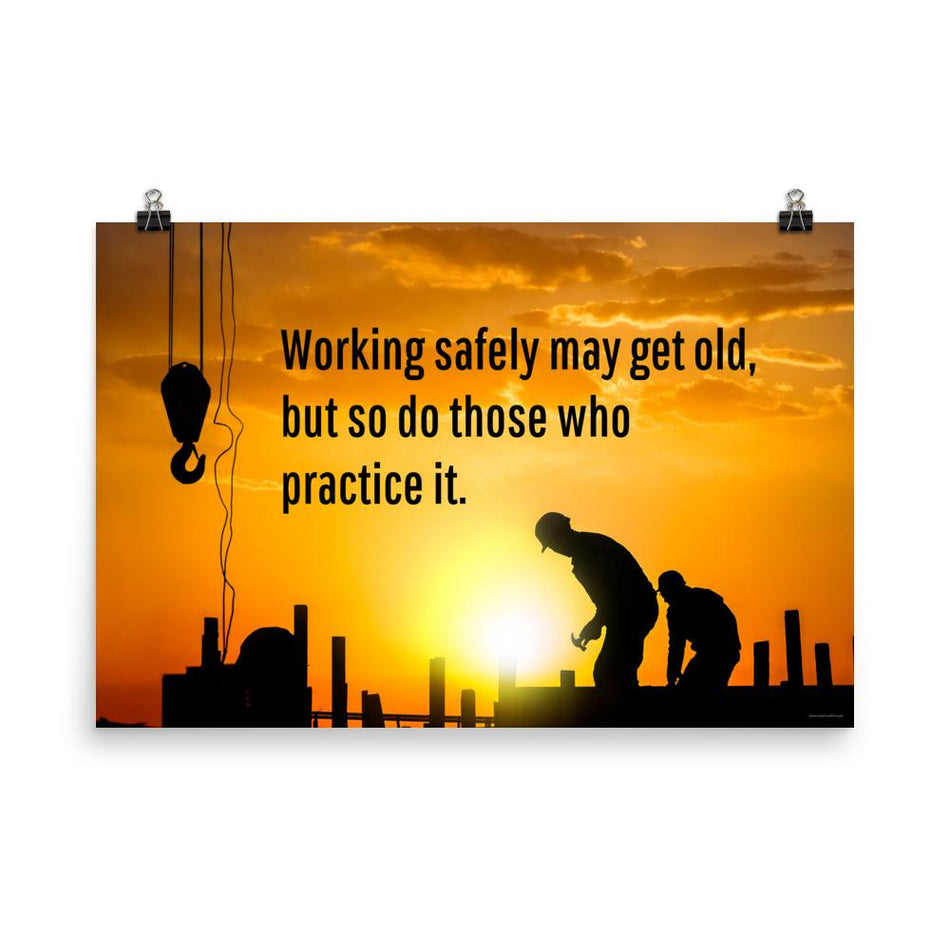 A workplace safety poster showing a construction site and construction workers being silhouetted by a bright and beautiful sunset of different shades of orange with the slogan working safely may get old, but so do those who practice it.