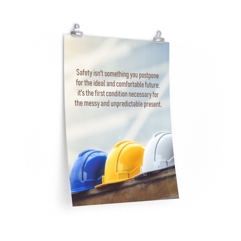 A workplace safety poster showing 3 multi colored hardhats sitting on a wall with the slogan safety isn't something you postpone for the ideal and comfortable future. It's the first condition necessary for the messy and unpredictable present.