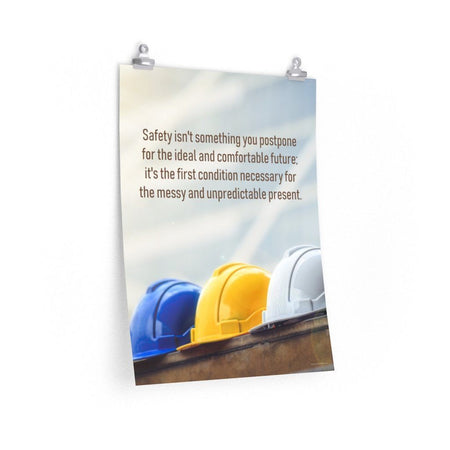 A workplace safety poster showing 3 multi colored hardhats sitting on a wall with the slogan safety isn't something you postpone for the ideal and comfortable future. It's the first condition necessary for the messy and unpredictable present.