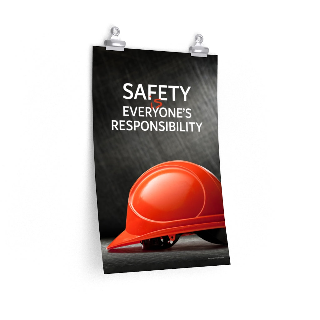 A workplace safety poster showing a red hard hat in front of a grey, industrial-looking background with the slogan safety is everyone's responsibility.