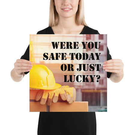 A workplace safety poster showing a yellow hard hat and some gloves sitting on a brick wall on a construction site with the slogan were you safe today, or just lucky written in black stencil font.
