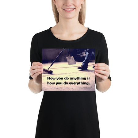 Safety poster showing a closeup of the ground where a warehouse or construction worker is sweeping the workshop floor and an encouraging safety slogan written in bold text.