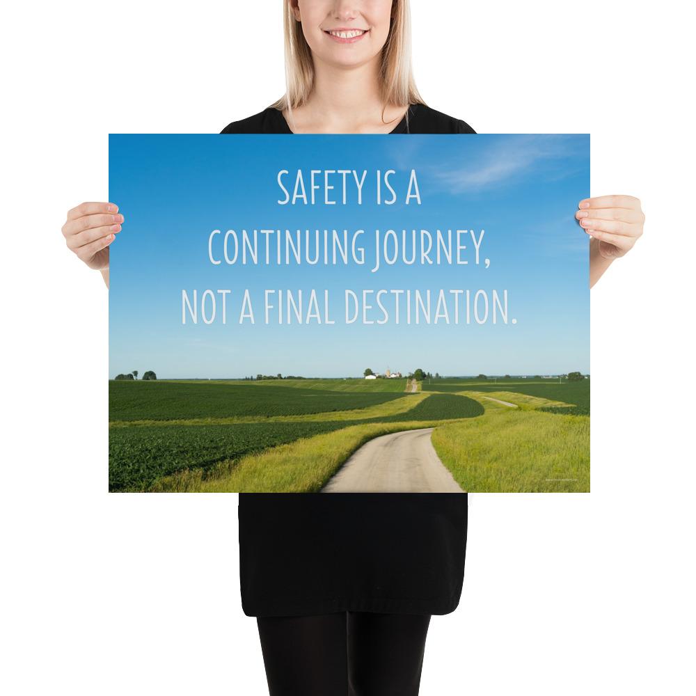 A workplace safety poster depicting a beautiful sunny day with a bright blue sky and a lush green field being cut down the middle by a dirt road leading off into the countryside with the text safety is a continuing journey, not a final destination.