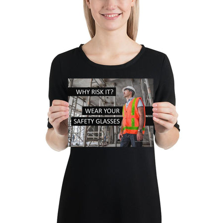 A safety poster showing a construction worker in a reflective orange vest, hard hat, and safety glasses on a construction site looking out with a safety slogan to the left.