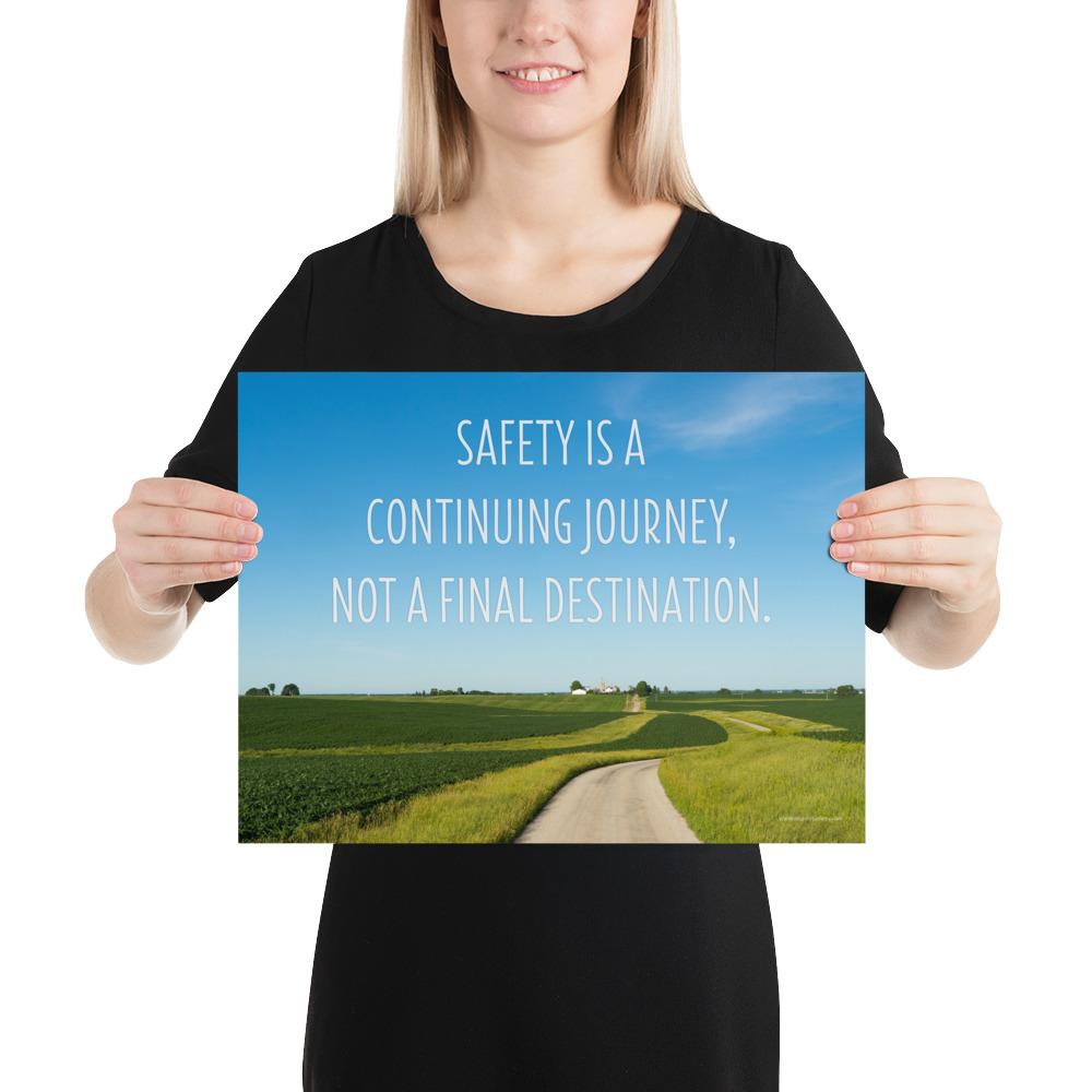 A workplace safety poster depicting a beautiful sunny day with a bright blue sky and a lush green field being cut down the middle by a dirt road leading off into the countryside with the text safety is a continuing journey, not a final destination.