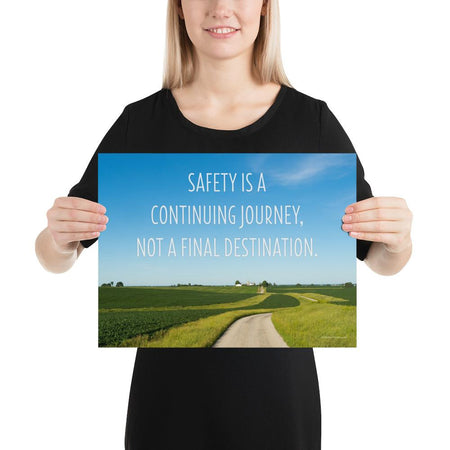 A workplace safety poster depicting a beautiful sunny day with a bright blue sky and a lush green field being cut down the middle by a dirt road leading off into the countryside with the text safety is a continuing journey, not a final destination.