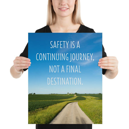 A workplace safety poster depicting a beautiful sunny day with a bright blue sky and a lush green field being cut down the middle by a dirt road leading off into the countryside with the text safety is a continuing journey, not a final destination.