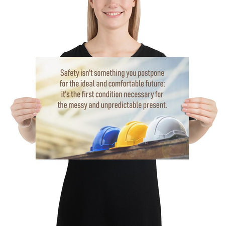 A workplace safety poster showing 3 multi colored hardhats sitting on a wall with the slogan safety isn't something you postpone for the ideal and comfortable future. It's the first condition necessary for the messy and unpredictable present.