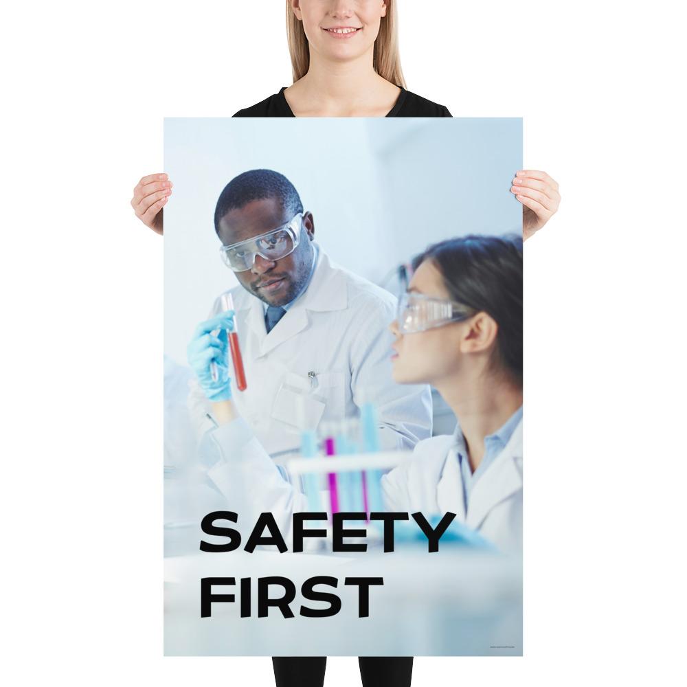 A safety poster showing two lab workers collaborating on a project in a lab while wearing full PPE with the slogan safety first.