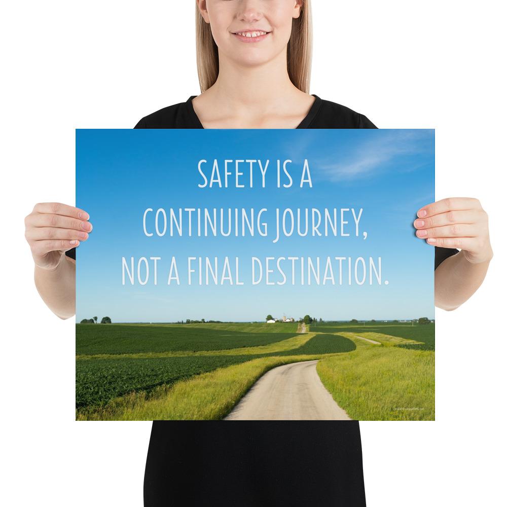 A workplace safety poster depicting a beautiful sunny day with a bright blue sky and a lush green field being cut down the middle by a dirt road leading off into the countryside with the text safety is a continuing journey, not a final destination.