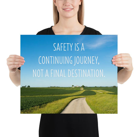 A workplace safety poster depicting a beautiful sunny day with a bright blue sky and a lush green field being cut down the middle by a dirt road leading off into the countryside with the text safety is a continuing journey, not a final destination.