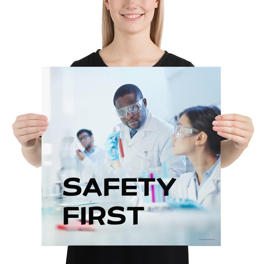 A safety poster showing two lab workers collaborating on a project in a lab while wearing full PPE with the slogan safety first.
