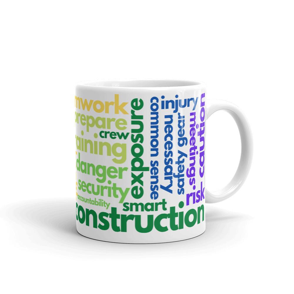 White ceramic mug with safety terms like hard hats, protection, and encourage, in a rainbow pattern across the mug.