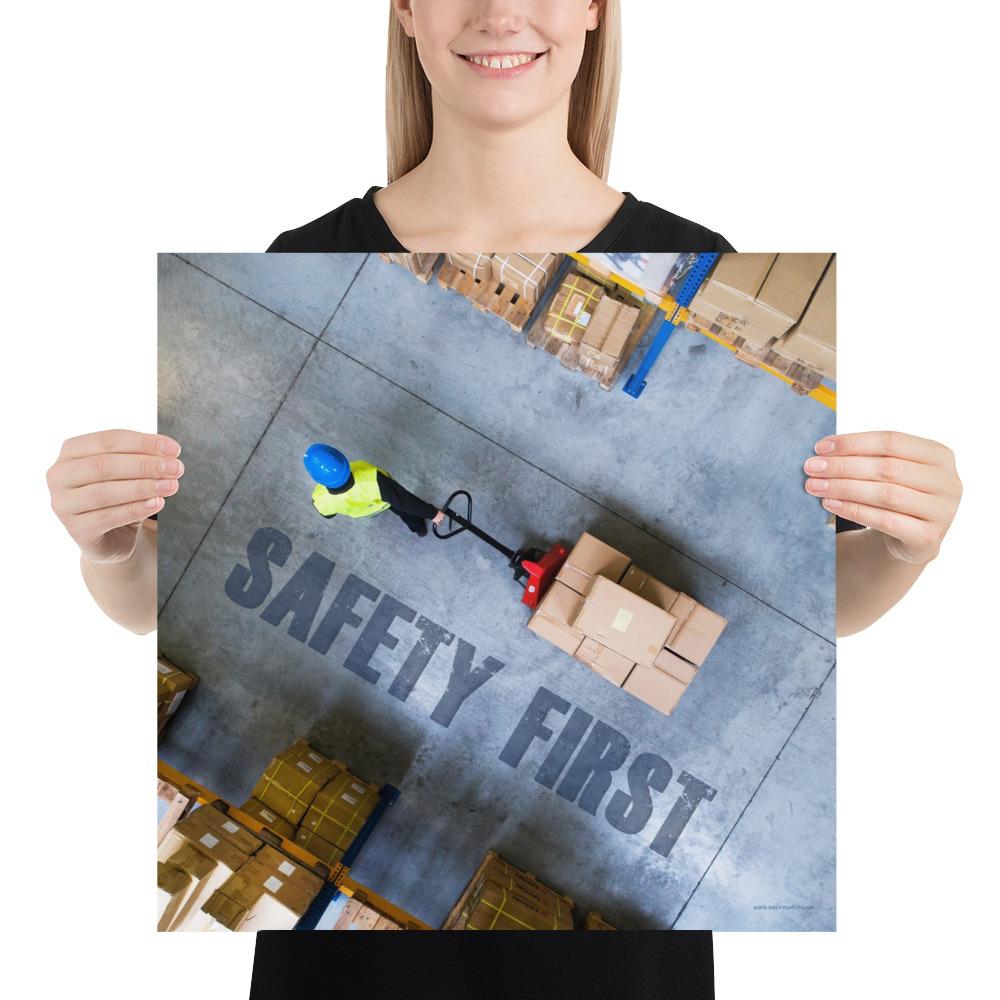 A safety poster showing a bird's-eye view of a worker in a warehouse pulling boxes on a pallet jack with the slogan safety first in bold letters.