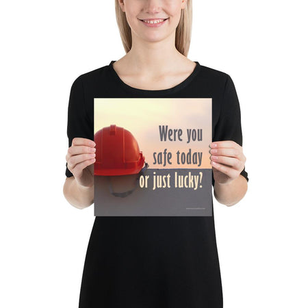 A workplace safety poster showing a red hard hat sitting on a grey wall with a dreamy sunset background and the slogan were you safe today, or just lucky?
