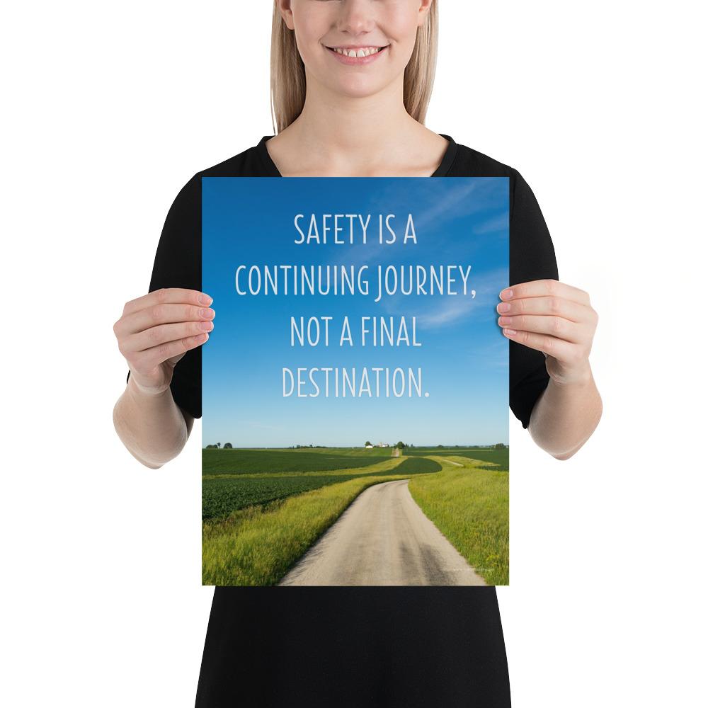 A workplace safety poster depicting a beautiful sunny day with a bright blue sky and a lush green field being cut down the middle by a dirt road leading off into the countryside with the text safety is a continuing journey, not a final destination.