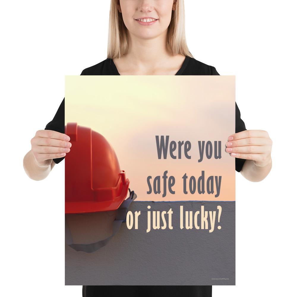 A workplace safety poster showing a red hard hat sitting on a grey wall with a dreamy sunset background and the slogan were you safe today, or just lucky?