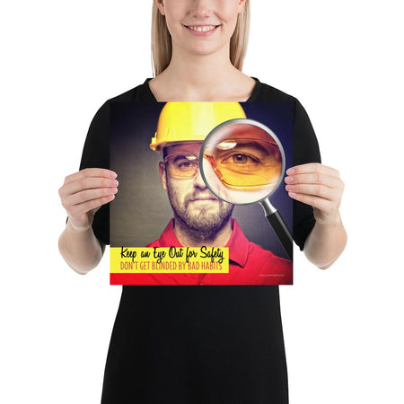 A workplace safety poster showing a portrait of a man wearing a hardhat and safety glasses with a magnifying glass magnifying one eye with the slogan, keep an eye out for safety, don't get blinded by bad habits.