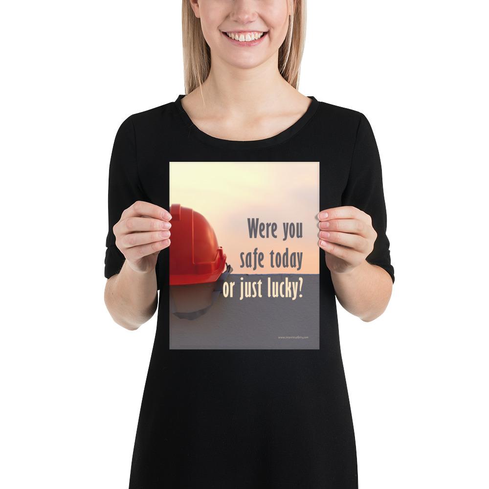 A workplace safety poster showing a red hard hat sitting on a grey wall with a dreamy sunset background and the slogan were you safe today, or just lucky?