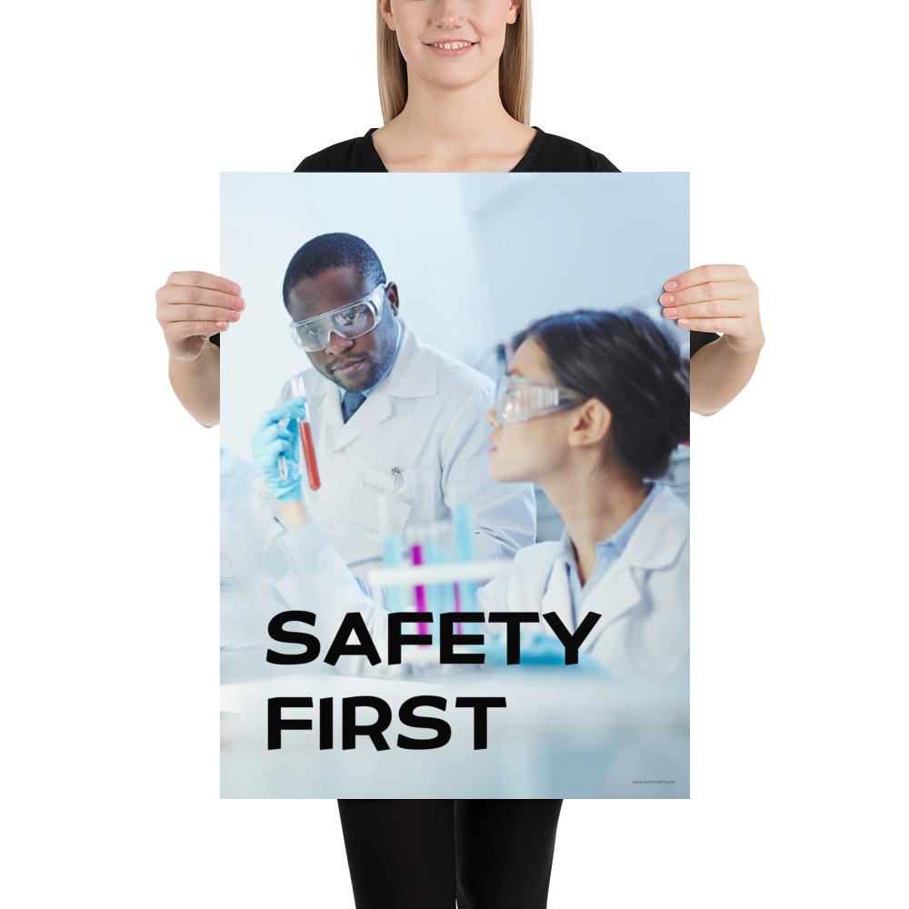 A safety poster showing two lab workers collaborating on a project in a lab while wearing full PPE with the slogan safety first.