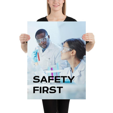 A safety poster showing two lab workers collaborating on a project in a lab while wearing full PPE with the slogan safety first.