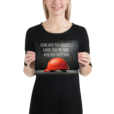 A workplace safety poster showing a bright red hard hat with an ominous black background with the slogan living with your mistakes is harder than you think, wear your safety gear.