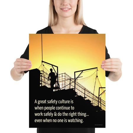 A construction safety poster showing the silhouette of a construction worker working on a building with a bright yellow sunset in the background and a safety slogan in the bottom left corner.