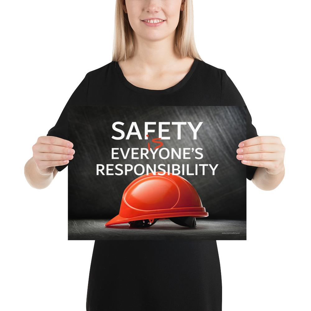 A workplace safety poster showing a red hard hat in front of a grey, industrial-looking background with the slogan safety is everyone's responsibility.