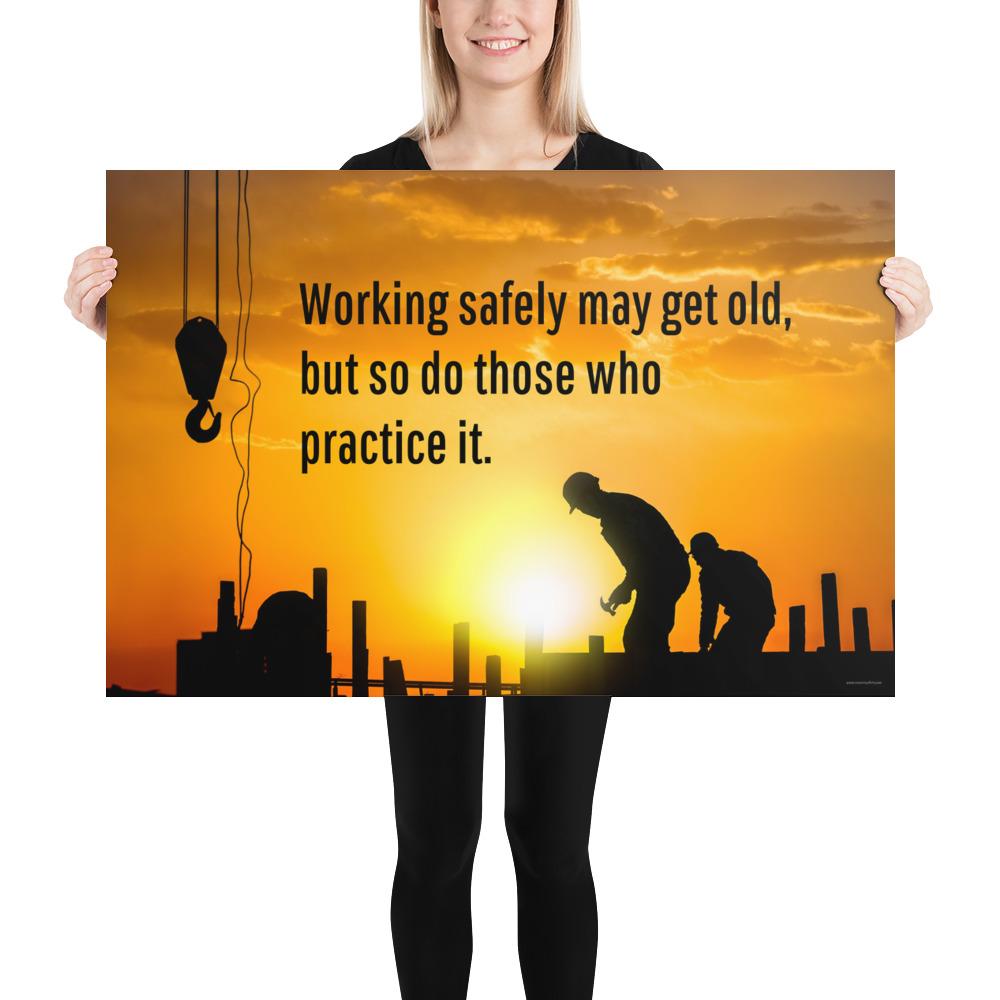 A workplace safety poster showing a construction site and construction workers being silhouetted by a bright and beautiful sunset of different shades of orange with the slogan working safely may get old, but so do those who practice it.