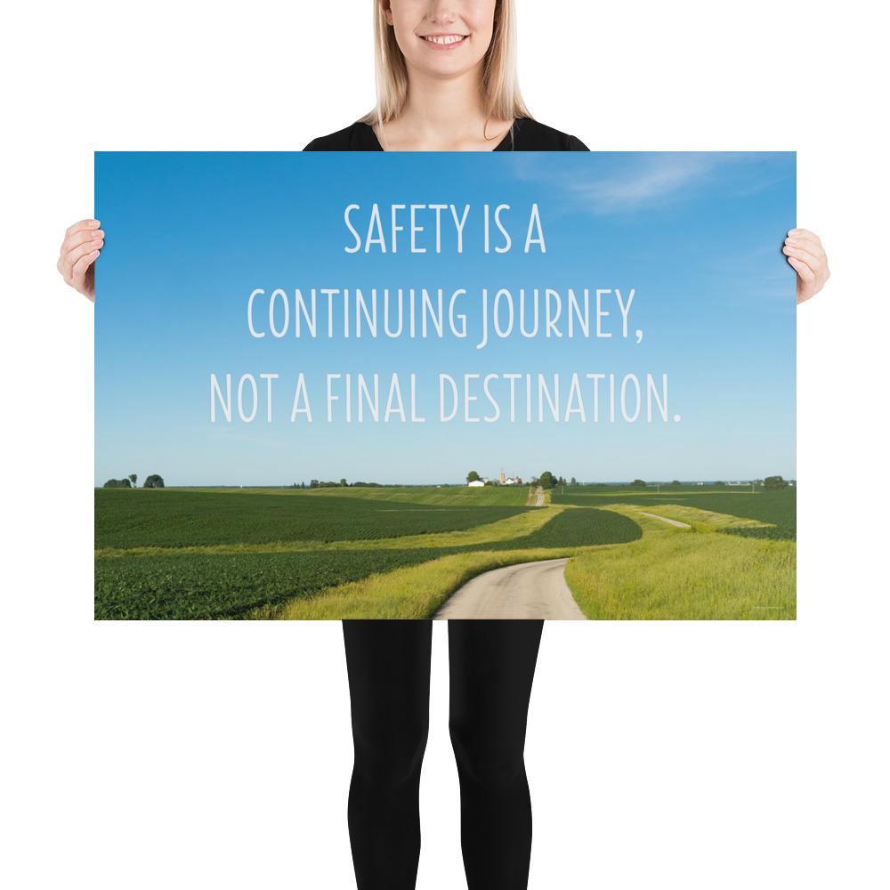 A workplace safety poster depicting a beautiful sunny day with a bright blue sky and a lush green field being cut down the middle by a dirt road leading off into the countryside with the text safety is a continuing journey, not a final destination.