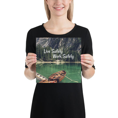 A workplace safety poster depicting a beautiful landscape of mountains in the background of a lake with a little wooden boat in the lake with text saying live safely work safely.