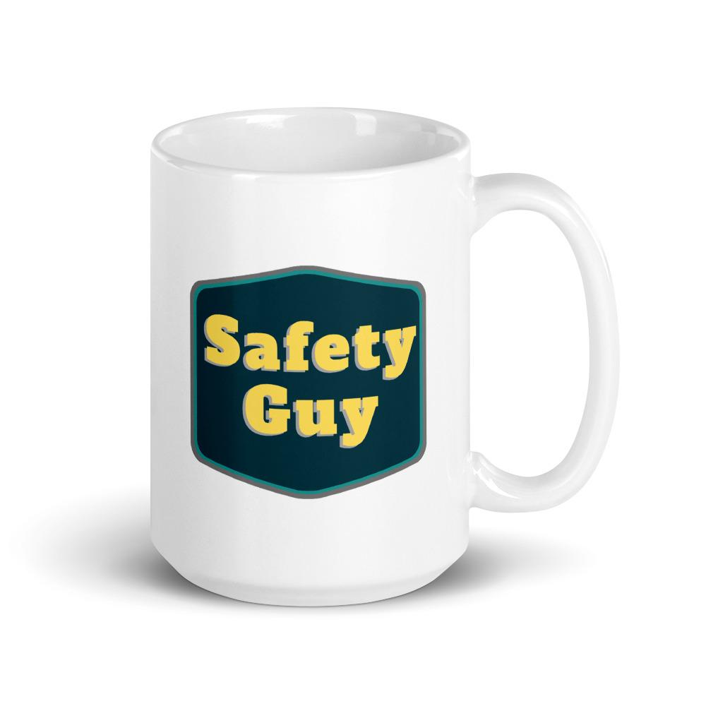 White ceramic mug with a navy emblem encasing bold yellow text that says "Safety Guy."