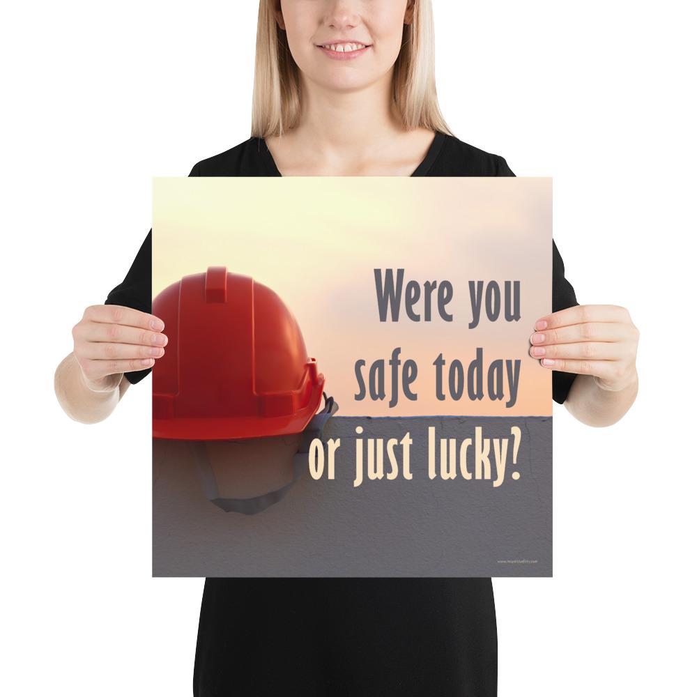 A workplace safety poster showing a red hard hat sitting on a grey wall with a dreamy sunset background and the slogan were you safe today, or just lucky?
