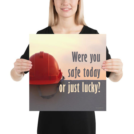 A workplace safety poster showing a red hard hat sitting on a grey wall with a dreamy sunset background and the slogan were you safe today, or just lucky?