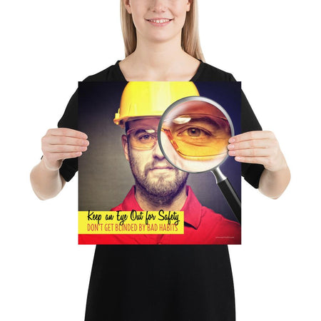 A workplace safety poster showing a portrait of a man wearing a hardhat and safety glasses with a magnifying glass magnifying one eye with the slogan, keep an eye out for safety, don't get blinded by bad habits.