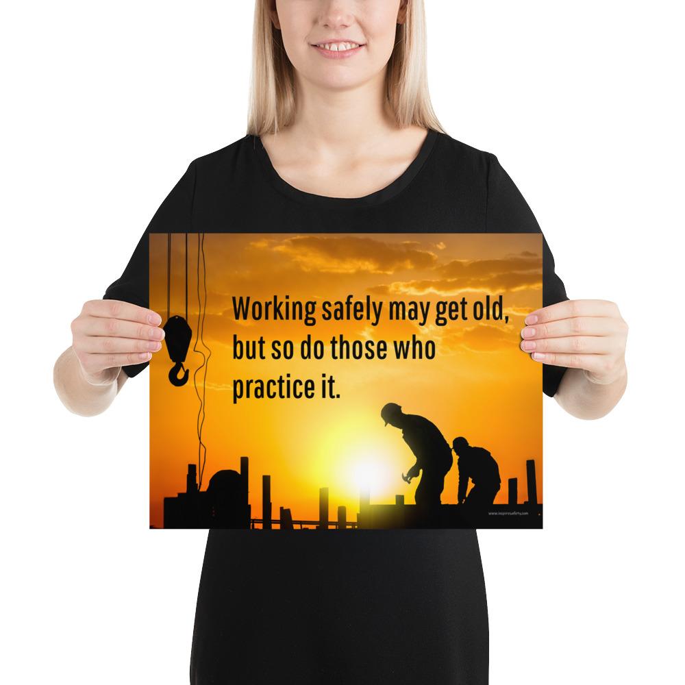 A workplace safety poster showing a construction site and construction workers being silhouetted by a bright and beautiful sunset of different shades of orange with the slogan working safely may get old, but so do those who practice it.