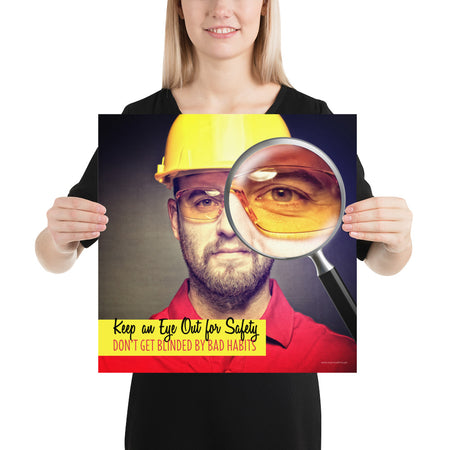 A workplace safety poster showing a portrait of a man wearing a hardhat and safety glasses with a magnifying glass magnifying one eye with the slogan, keep an eye out for safety, don't get blinded by bad habits.