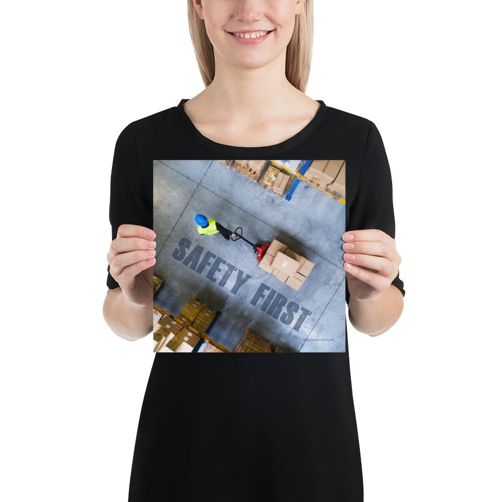 A safety poster showing a bird's-eye view of a worker in a warehouse pulling boxes on a pallet jack with the slogan safety first in bold letters.