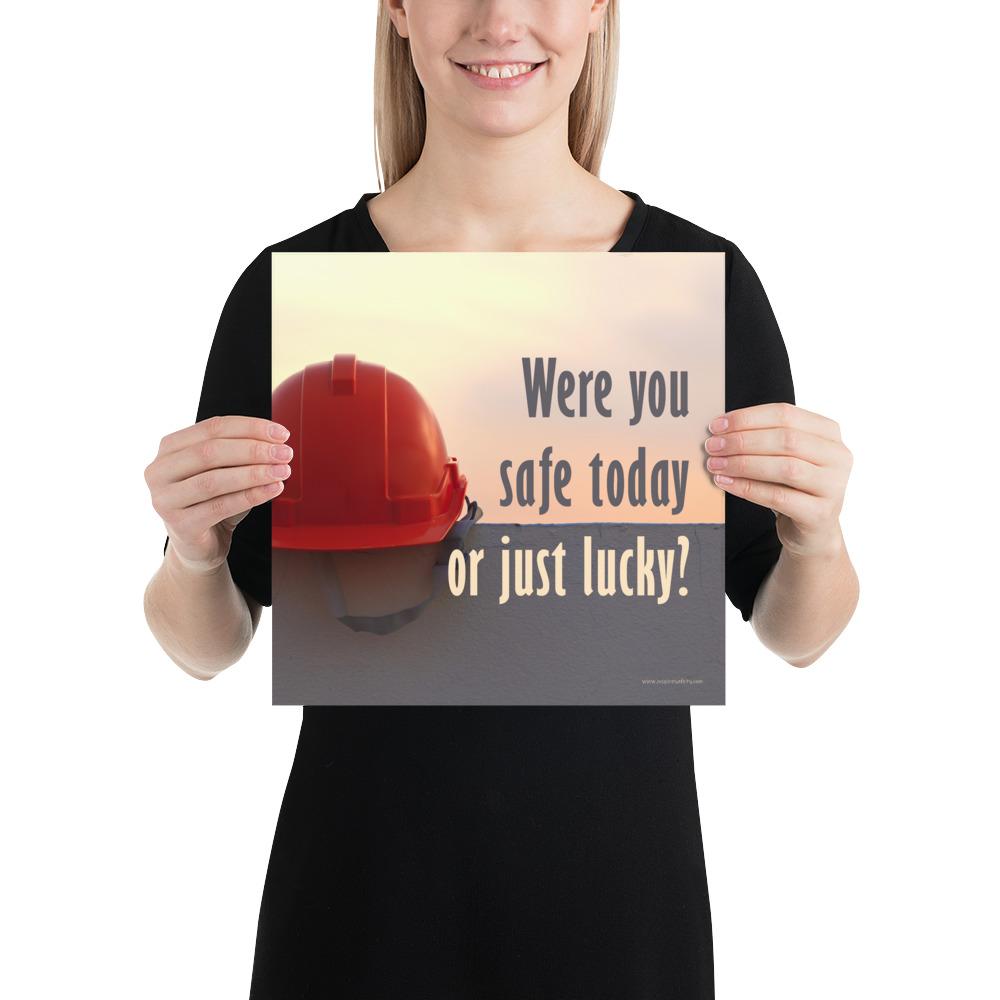 A workplace safety poster showing a red hard hat sitting on a grey wall with a dreamy sunset background and the slogan were you safe today, or just lucky?